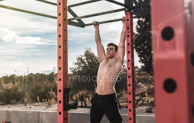 Young fitness man doing chin-ups outdoors — Stock Photo