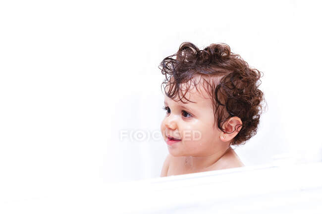Entzückendes Baby schaut mit nassen Haaren weg, während es im Badezimmer badet — Stockfoto