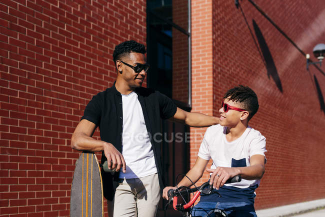 Smiling black male friends with bicycle and skateboard — Stock Photo