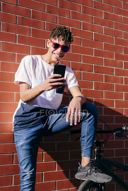 Giovane felice uomo nero smartphone di navigazione in bicicletta — Foto stock