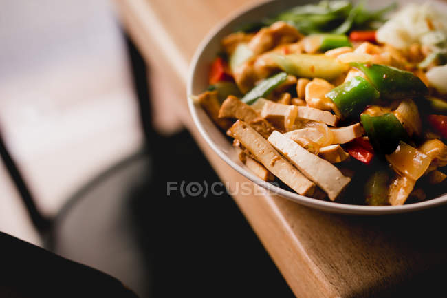 Schüssel mit leckerem vegetarischem Gericht mit Gemüse auf Holztisch — Stockfoto