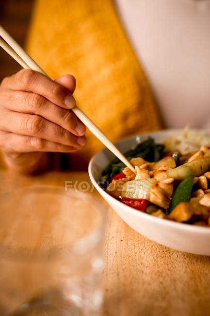 Schüssel mit leckerem vegetarischem Gericht mit Gemüse mit weiblicher Hand, die Essstäbchen hält — Stockfoto