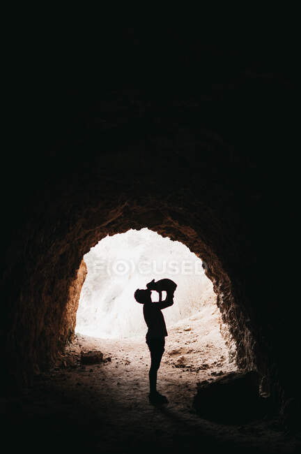 Путешественник играет с собакой в темной пещере — стоковое фото