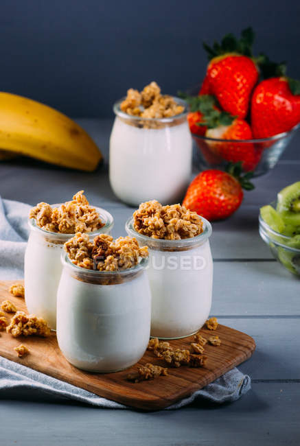 Vasos de leche fría y deliciosa granola sobre tabla de madera - foto de stock