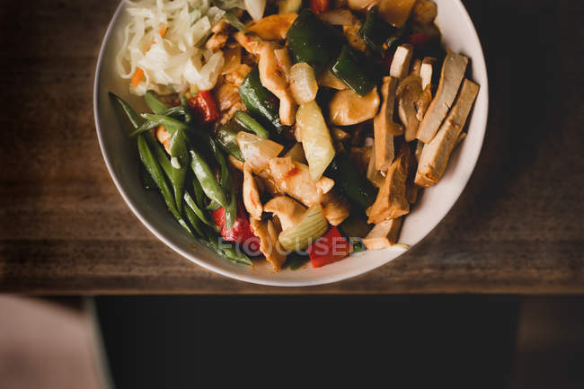 Bowl of tasty vegetarian dish with vegetables on wooden table — Stock Photo