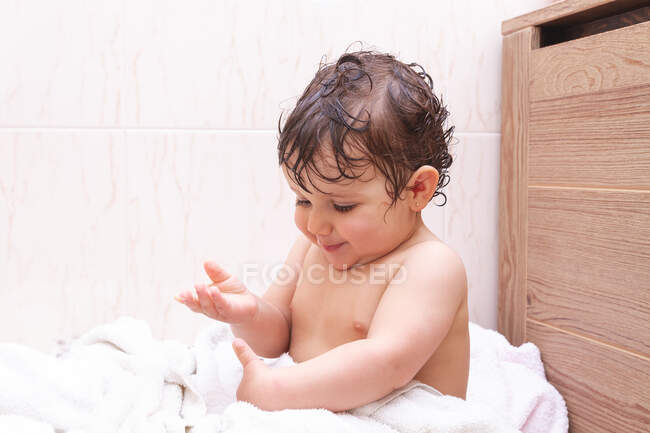 Adorable bébé aux cheveux mouillés assis sur une serviette dans la salle de bain après la douche — Photo de stock