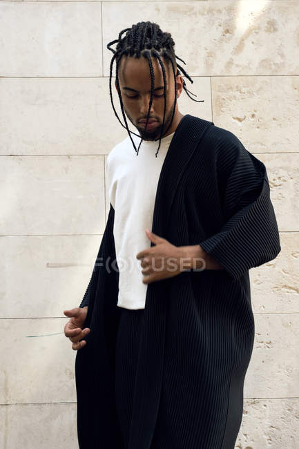 Moda jovem afro-americano masculino em roupa elegante posando na rua perto da parede grungy — Fotografia de Stock