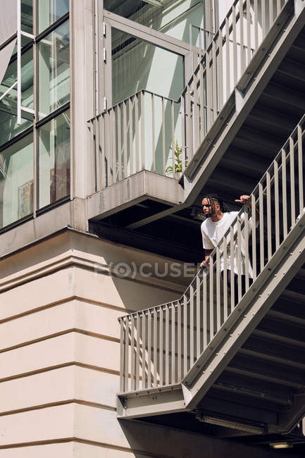 Young African American man leaning on railing of bridge in city — Stock Photo