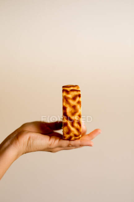 Mão segurando fatia de delicioso bolo de banana doce fresco no fundo marrom — Fotografia de Stock