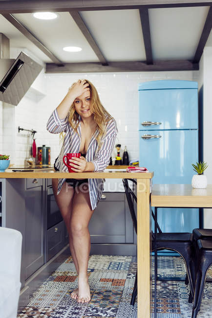 Молодая женщина держит горячий чай на кухне — стоковое фото