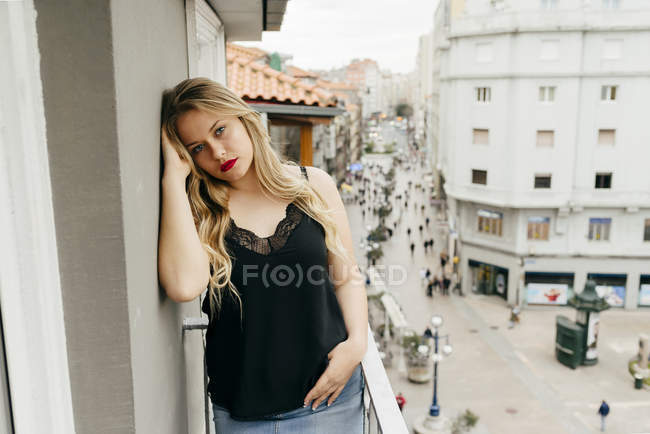 Junge Frau blickt auf Balkon in Kamera — Stockfoto