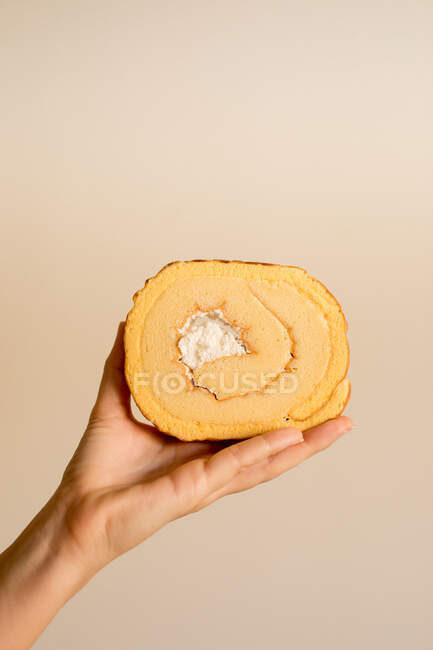 Mão segurando fatia de delicioso bolo de banana doce fresco no fundo marrom — Fotografia de Stock