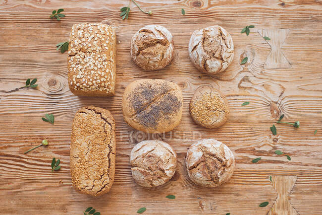 D'en haut composition de pains chauds, pains, petits pains et baguettes sur table en bois dans la boulangerie — Photo de stock