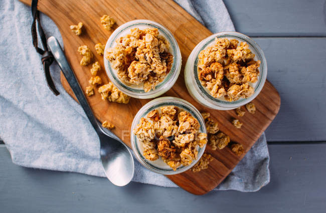 Glasses of cold tasty milk and delicious granola on wooden board — Stock Photo