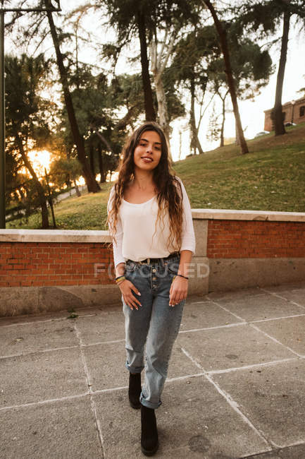 Hübsche junge Frau in lässigem Outfit, die an einem sonnigen Tag im Park in die Kamera lächelt — Stockfoto
