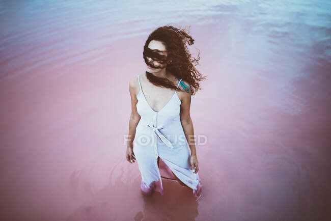 Jeune belle femme avec de longs cheveux bouclés portant une robe d'été profitant de la brise de mer — Photo de stock