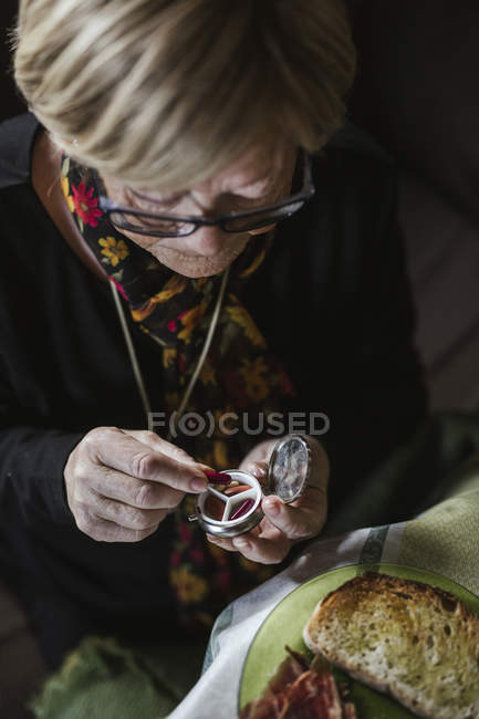 Mão de mulher idosa tomando pílula vermelha de caixa de pílula de aço — Fotografia de Stock