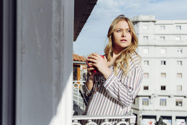 Молода жінка з чашкою на терасі — стокове фото