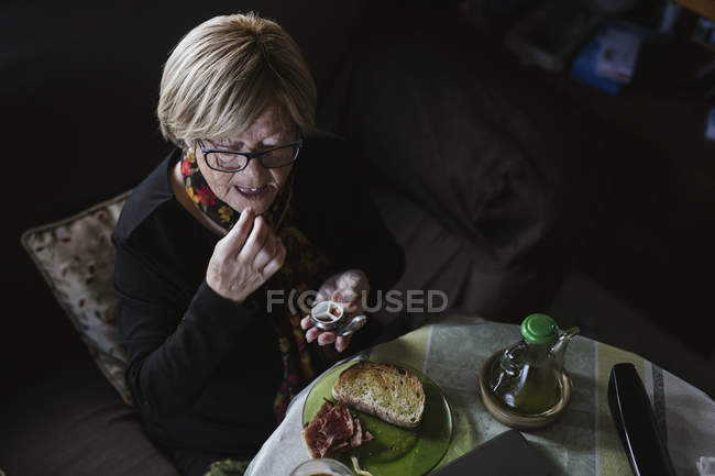 Senior attractive woman taking medication from pill box before breakfast — Stock Photo