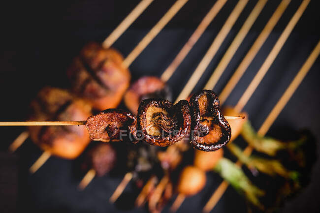 From above cooked hot mushroom skewer over table with delicious grilled skewers with meat, fish, squid and broccoli — Stock Photo