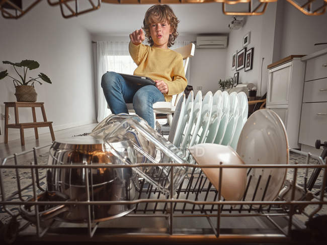 Boy smiling looking inside open dishwasher in kitchen — Stock Photo