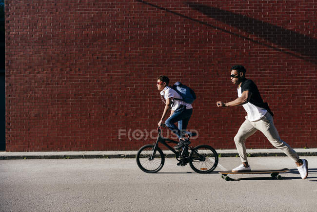 Junge afrikanisch-amerikanische Männer auf Fahrrad und Skateboard — Stockfoto