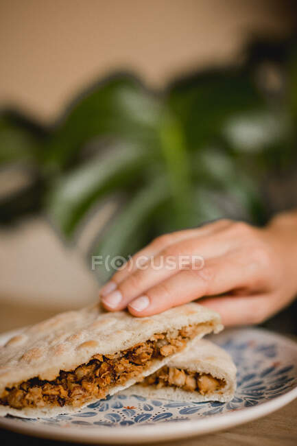Hand holding served appetizing Chinese burgers with pork, star anise, cinnamon and hot steamed bun on plate in Asian cafe - foto de stock