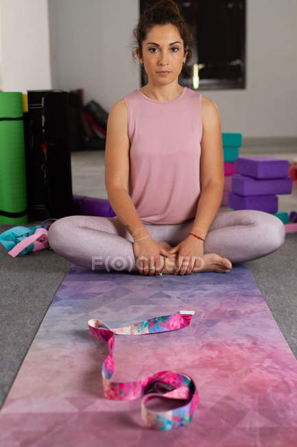 Jovem morena séria em sportswear sentado na posição de ioga e olhando para a câmera — Fotografia de Stock