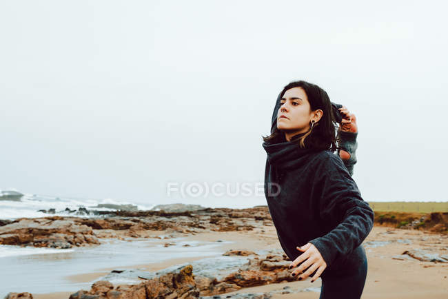 Young woman stretching on rocks near sea — Stock Photo