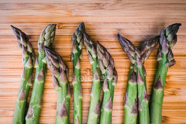 Closeup of bunch of fresh green asparagus on wooden surface — Stock Photo