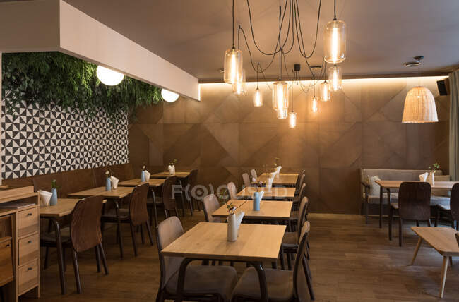 Stylish lamp shining over small tables and comfortable chairs in cozy restaurant — Stock Photo