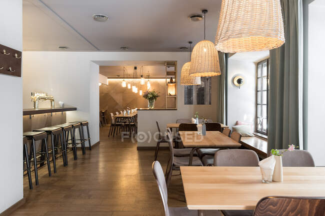 Elegante lámpara que brilla sobre pequeñas mesas y cómodas sillas en el acogedor restaurante - foto de stock