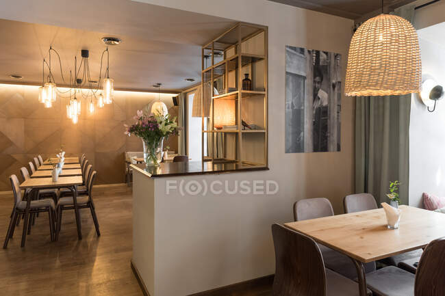 Lâmpada elegante brilhando sobre pequenas mesas e cadeiras confortáveis no restaurante acolhedor — Fotografia de Stock