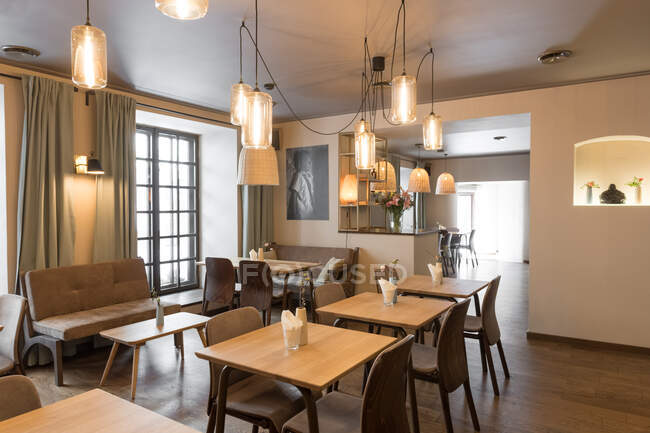 Стильна лампа, що світиться над невеликими столиками і зручними стільцями в затишному ресторані — стокове фото