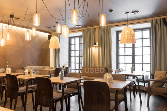 Elegante lampada splendente su tavolini e comode sedie in accogliente ristorante — Foto stock