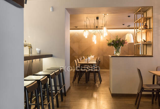 Стильная лампа, сияющая над маленькими столами и удобными стульями в уютном ресторане — стоковое фото