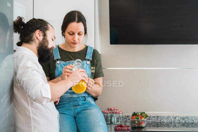 Barbudo hombre alimentación novia con comida saludable, mientras que pasar tiempo en la cocina en casa juntos - foto de stock