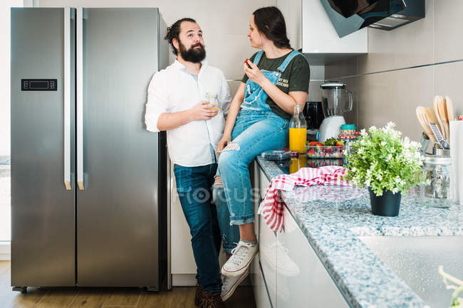 Пара пьет апельсиновый сок и питается здоровой пищей, проводя время на кухне вместе — стоковое фото