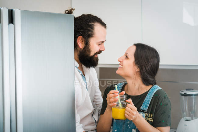 Пара п'є апельсиновий сік і їсть здорову їжу, проводячи час на кухні вдома разом — стокове фото