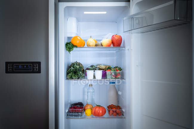 Shelf of refrigerator full of healthy food at home — Stock Photo