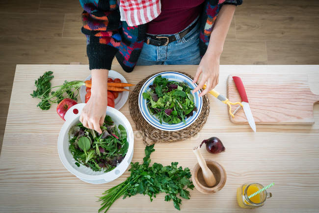 Hände einer Frau, die Gemüse zubereitet, während sie in der Küche gesunden Salat zubereitet — Stockfoto