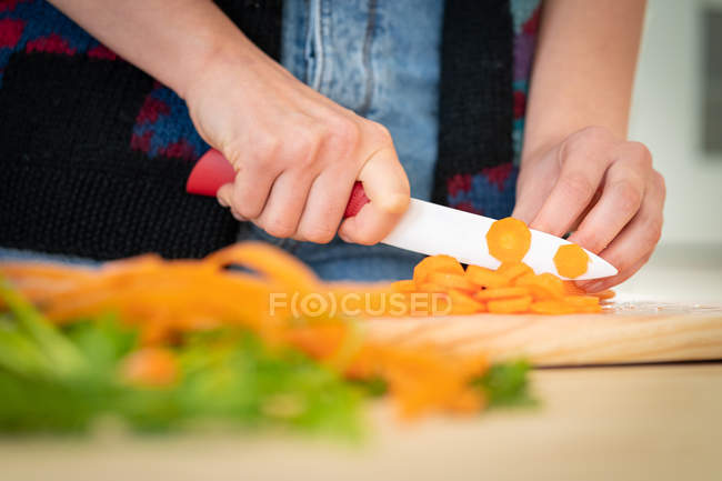 Cropped image of woman cutting carrots while cooking healthy salad in kitchen — Stock Photo