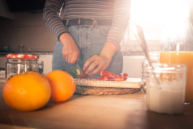 Immagine ritagliata di donna in abito casual tagliare fragole fresche in cucina — Foto stock