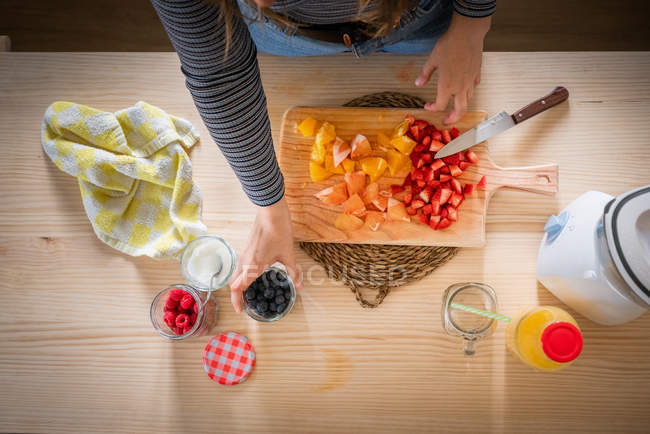 V prendre des bleuets dans un bocal tout en cuisinant des aliments vitaminés sains à partir de fruits frais à la maison — Photo de stock
