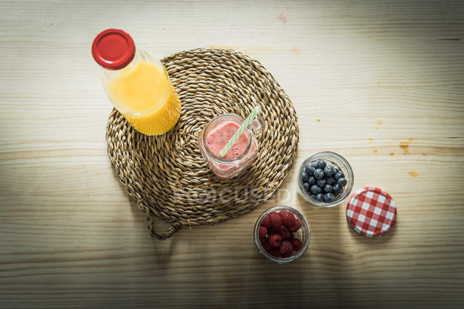 Containers with fresh berries and healthy beverages placed on table — Stock Photo