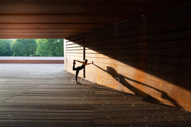 Junge Frau dehnt sich nach dem Laufen und lehnt sich in einem erstaunlichen geometrischen Gebäude — Stockfoto