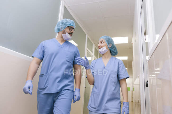 Fellow surgeons man and woman chat while walking towards the operating theater — Stock Photo