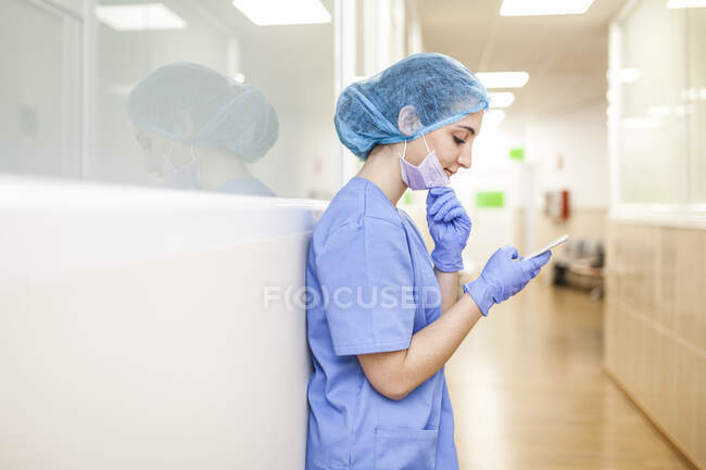 Female surgeon rests while checking messages on her smartphone — Stock Photo