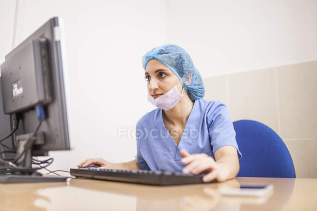 Female surgeon using her computer in her office before the surgery — Stock Photo
