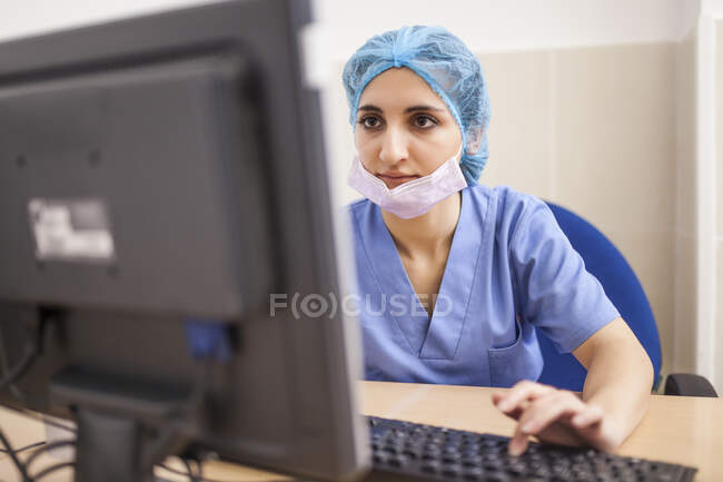 Cirurgiã usando seu computador em seu escritório antes da cirurgia — Fotografia de Stock